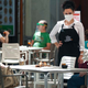 A waitress wearing a face mask chatting with customers at the terrace of a bar